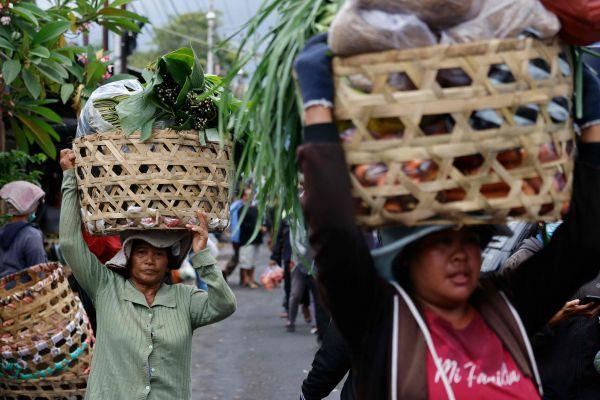 在印尼巴厘岛的一处市场，摊贩们正在搬运商品。（法新社）