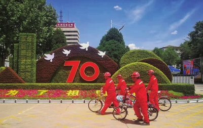 员工经过厂区庆祝中华人民共和国70周年花坛。　□冯作文摄